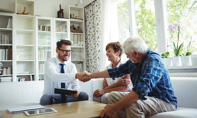 financial advisor shaking hands with senior couple in their living room safe retirement plan